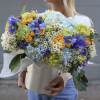 Large bouquet of blue, yellow, and green flowers wrapped in white paper