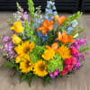 A colorful arrangement featuring sunflowers, orange lilies, yellow roses, pink carnations, green