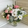 A charming arrangement of fresh white daisies and soft blush blooms, accented