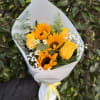 A radiant wrapped handheld bouquet of sunflowers and yellow roses, accented with