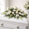 A graceful and timeless casket spray featuring white roses, lilies, and delicate