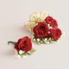 This elegant corsage and boutonniere set, featuring vibrant red blooms, is thoughtfully