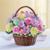 A basket full of daisies, carnations, filler and roses in a pastel