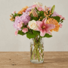 Mixed bouquet of pink lilies, lavender mums, white roses and peach blooms in a clear glass vase