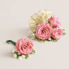 This striking corsage and boutonniere set, featuring delicate light pink blooms, is