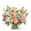 Bouquet of peach roses and white lilies in a clear glass vase