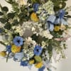 A permanent wreath with white and yellow faux blooms and decorated with