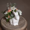 An adorable ceramic rabbit planter is filled with festive foliage and pastel