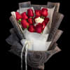 Hand-tied bouquet of red roses wrapped in dark paper with a small white teddy bear.