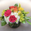 This arrangement has hydrangea, orange roses, yellow tulips, yellow alstroemeria, hot pink