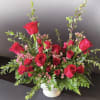This arrangement has red roses, pray roses, wax flower and greenery 