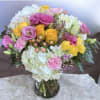 This arrangement has hydrangea, roses, spray roses, Carnations, lisianthus, hypericum, wax flower
