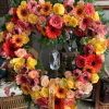 Heart-shaped standing wreath of pink, yellow, and orange roses and gerbera daisies on an easel with ribbon.