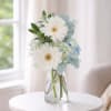 Soft blue and white blooms arranged in a clear vase for a