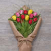 Bouquet of red, pink, and yellow tulips wrapped in brown paper