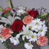 A lush blend of red roses, white lilies and daisies, and peach