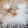 A soft white 8" x 8" ring bearer pillow edged in a