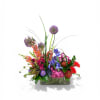 Tall purple allium-like blooms and sculptural grasses crown a low, elongated bouquet