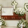 Pure white blooms arranged with generous green foliage create a calm, reverent