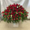 Large dome of red roses with one white flower and cascading palm fronds on a pedestal.