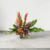 Tropical arrangement with orange roses, protea, purple orchids, and red heliconia in a low glass vase