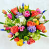 Gorgeous and vibrant spring flowers cluster in a large glass vase.