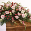 Always Beloved is a romantic red and pink casket spray designed to