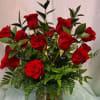 A lush cluster of velvety red roses arranged in a clear glass