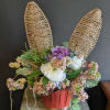 A charming faux spring flower arrangement nestled in a rustic basket, topped