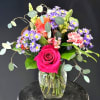 A vivid hot pink rose anchors this mixed flower arrangement, giving it