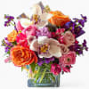 Lovely roses orchids and more arranged in a modern glass cube vase.