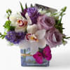 Bouquet of lavender roses, white orchids, and purple flowers in a glass vase