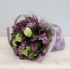 Bouquet of purple lilacs with green hydrangea in pink wrap