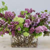 Pink and purple lilac arrangement in a glass vase with pebbles