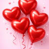 Cluster of red heart-shaped balloons with curly ribbons on a pink background with small hearts.