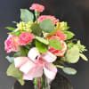 Rounded clusters of bright pink carnations and variegated pink roses give this