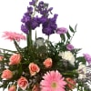 Soft pink gerbera daisies and peach-pink roses surround a clear glass angel