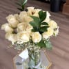 Bouquet of white roses in a clear glass vase with greenery