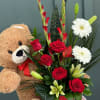 Red roses and white lilies in a red box with a teddy bear