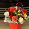 Colorful flower arrangement in a red handled gift bag