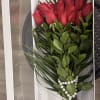 Red roses arranged in a white gift box with pearl accents