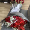 Bouquet of red roses with white baby's breath wrapped in gray paper