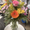 Mixed bouquet in a clear glass vase with pink, orange, yellow, and lavender flowers