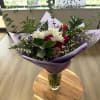 Bouquet of red and white flowers in purple wrap with a glass vase