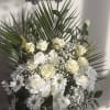 White floral arrangement with roses and daisies in a white container