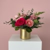 A gold pot filled with shades of pink flowers and foliage. Something