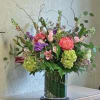 Tall mixed arrangement of pink, green, and purple flowers in a clear glass cylinder vase