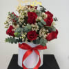 Red roses and white filler flowers in a white hat box with a red ribbon