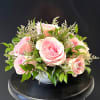 A compact dome of soft pink roses forms the centerpiece of this