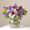 Mixed bouquet of daisies, carnations, and purple blooms in a glass vase